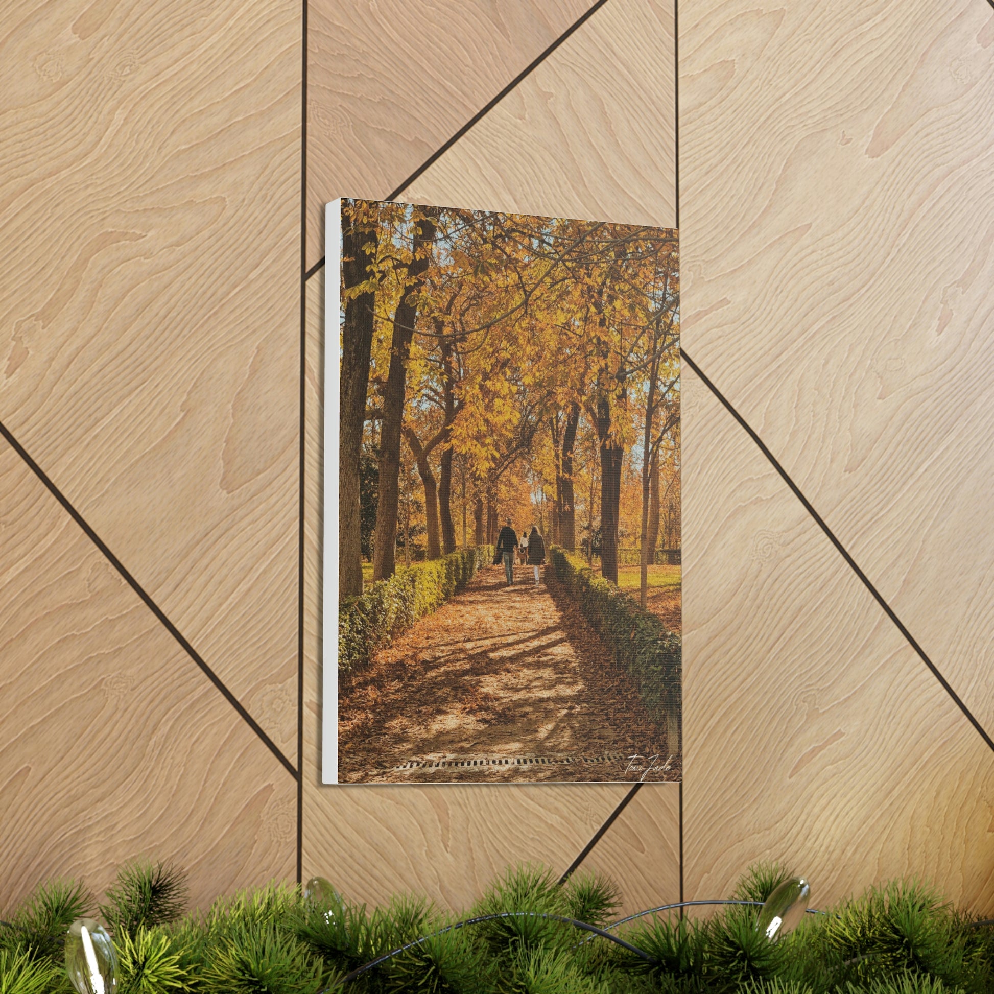 Our fall wall art in Spain is very colorful and vibrant. A couple is walking on the park trail with other families in front, the bright yellow leaves surrounding them.