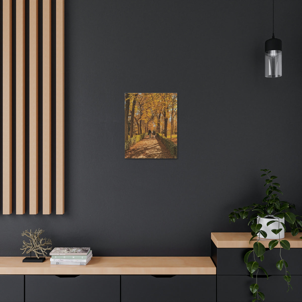 Our fall wall art in Spain is very colorful and vibrant. A couple is walking on the park trail with other families in front, the bright yellow leaves surrounding them.
